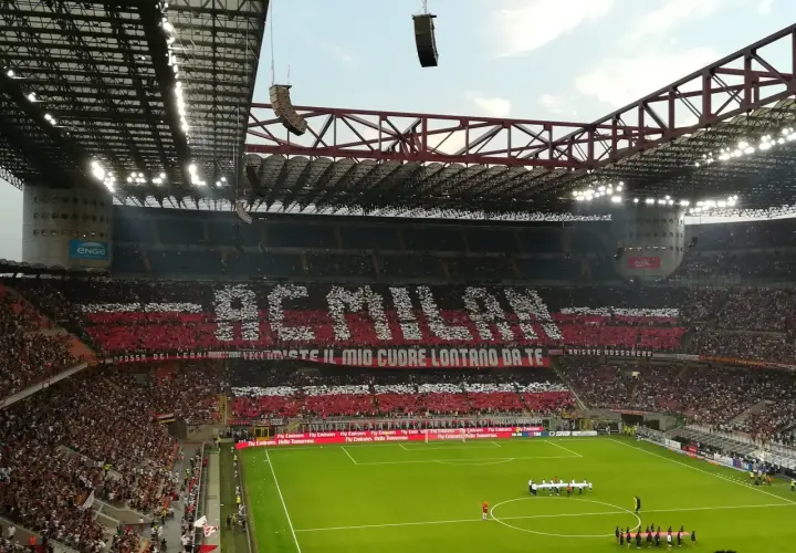 Wielki doping na mediolan stadionie. Trybuny tworzą napis "AC MILAN" i hasło kibiców.