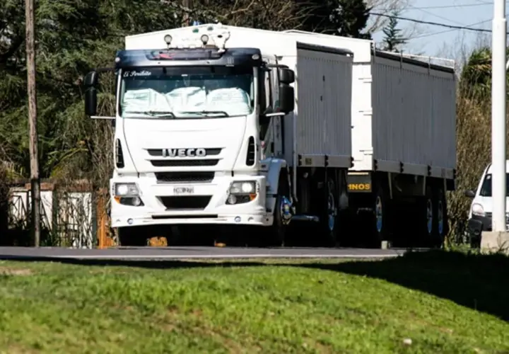 Biała ciężarówka Iveco z naczepą jedzie drogą. Kierowca ciężarówek wyrusza w długą trasę.