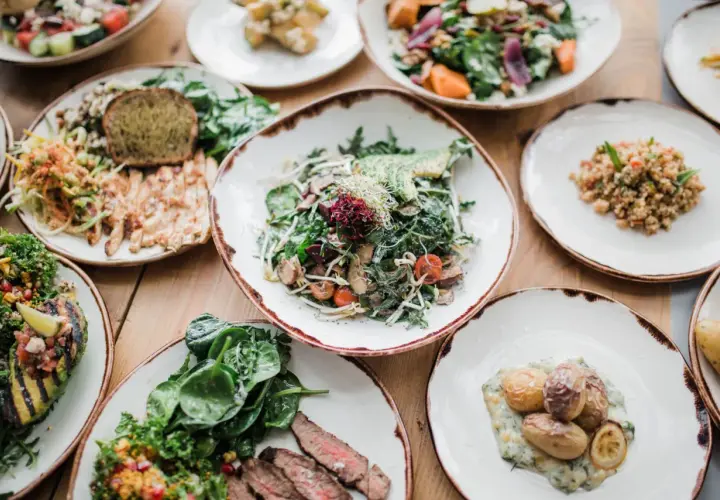 Variedad de platos saludables, incluyendo una ensalada de verdel con aguacate, pollo a la parrilla, quinoa y patatas asadas.