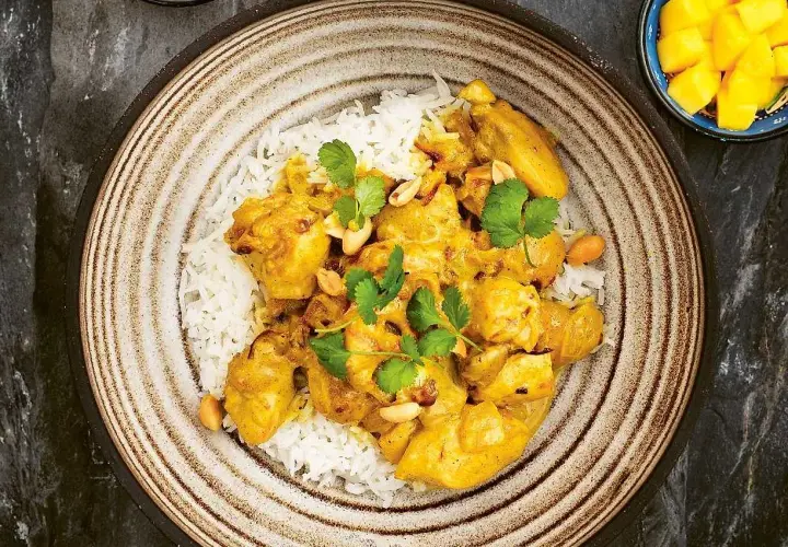 En krämig kycklingcurry med ris, toppad med koriander och jordnötter. En riktig curry nam nam!