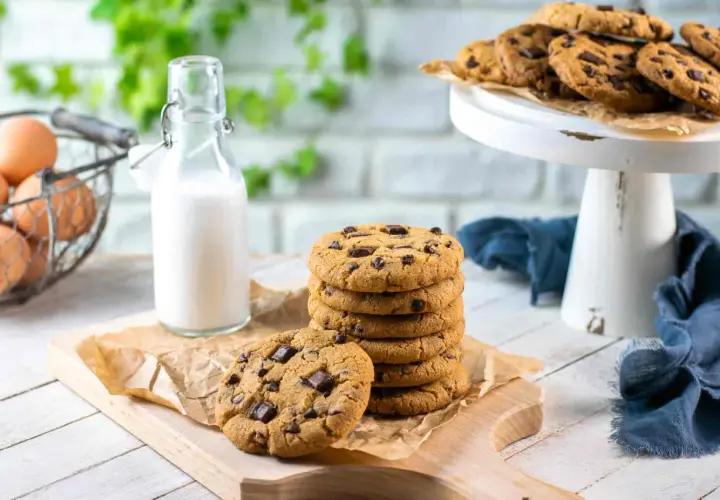 Una pila di biscotti con gocce di cioccolato, pronti per essere gustati con un bicchiere di latte.