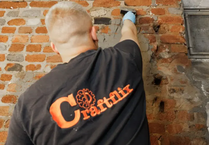 Handwerker mit Handschuh trägt Mörtel auf beschädigtes Mauerwerk auf, um das Injektionsverfahren durchzuführen.