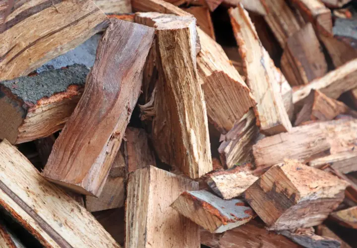 Stapel von gespaltenem Brennholz, bereit für den Kamin. Das Holz zeigt die Maserung und Rinde, die den hohen Brennwert beeinflussen.