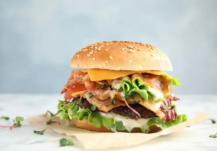 Apetyczny burger z bekonem, serem i warzywami. Czy zastanawiałeś się nad big mac kcal?