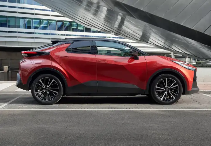 Nowoczesna, czerwona Toyota plug-in na tle futurystycznego budynku. Stylowy design i ekologiczna jazda.