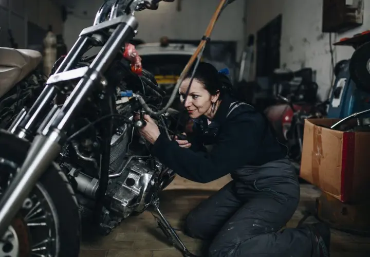 Mecánica arregla una moto ahogada en su taller.