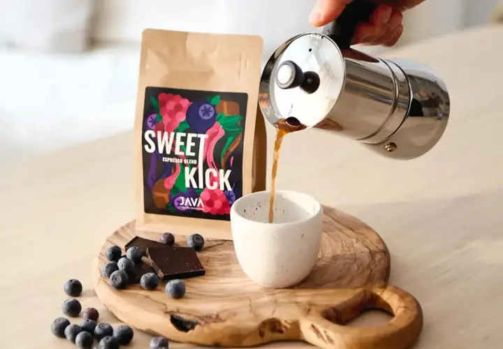 Kawa "Sweet Kick" z kawiarki nalewana do filiżanki. Na desce leżą jagody i czekolada. Idealna ilość kawy do kawiarki.