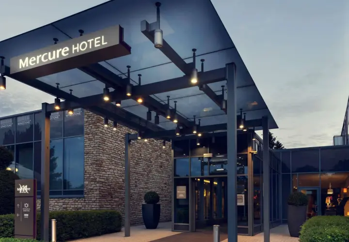 Nowoczesne wejście do hotelu Mercure w Gdańsku, z kamienną fasadą i szklanymi drzwiami.
