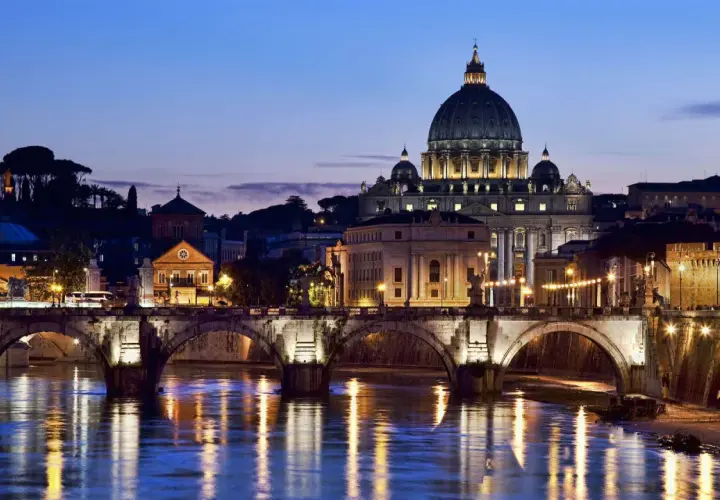 Un suggestivo ponte a Roma illumina il Tevere al crepuscolo, con San Pietro sullo sfondo.