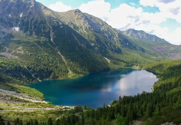 Widok na Morskie Oko, największe jezioro w Tatrach, otoczone stromymi, zalesionymi zboczami gór.