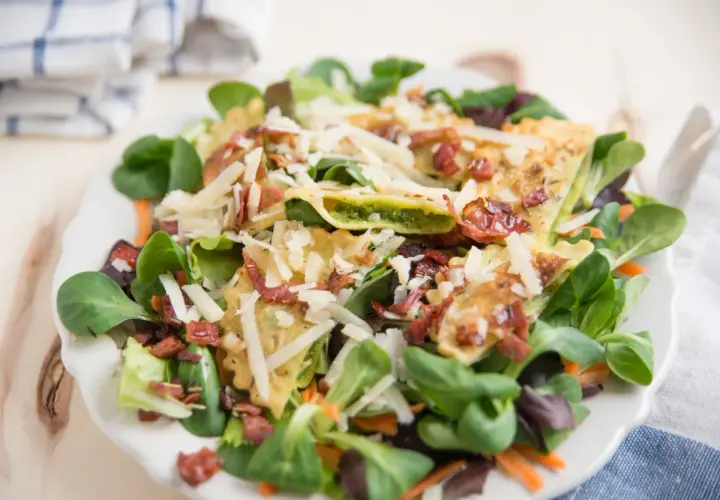 Pyszne ravioli z kurczakiem, podane na sałatce z parmezanem i chrupiącym boczkiem.