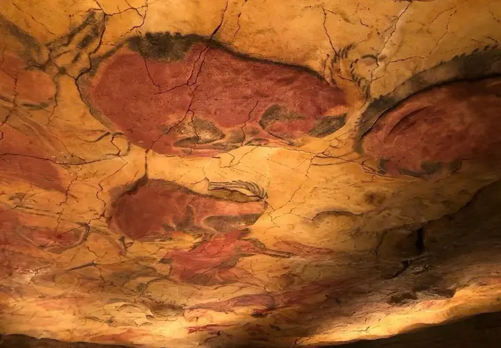 Pinturas rupestres de bisontes en el techo de una cueva, evocando el **museo mitológico Santillana del Mar**.