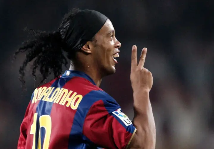 Piłkarz Ronaldinho w koszulce Barcelony, z charakterystyczną opaską na głowie i kucykiem, pokazuje dwa palce. Ile Ronaldinho ma lat?