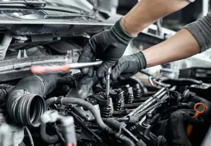 Mechanik naprawia zatarty silnik, używając klucza do dokręcenia części. Olej 0w20 mógł być przyczyną problemu.