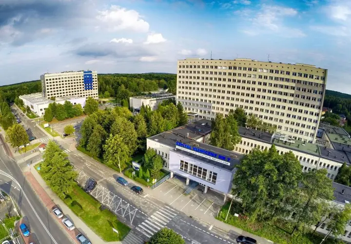 Widok z lotu ptaka na kompleks budynków szpitalnych otoczony zielenią.