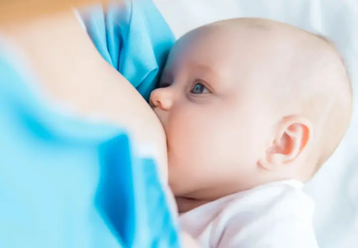 Un neonato si nutre al seno. La domanda su quanto deve mangiare un neonato è comune tra i neogenitori.