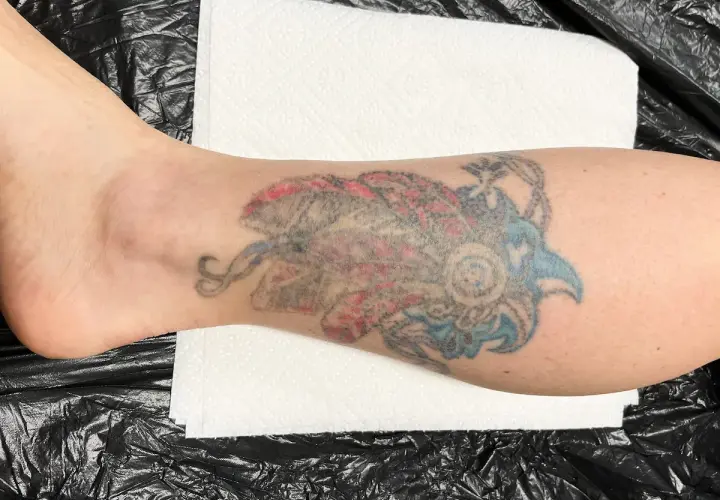 Kolorowy tatuaż w stylu irezumi polska na łydce, przedstawiający stylizowanego ptaka lub smoka.