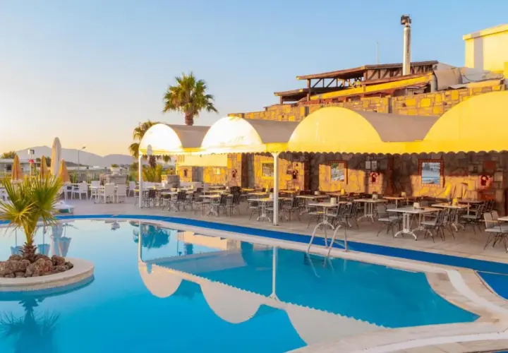 Basen i restauracja z żółtymi markizami w Sunpoint Hotel Bodrum. Idealne miejsce na relaks i posiłek.