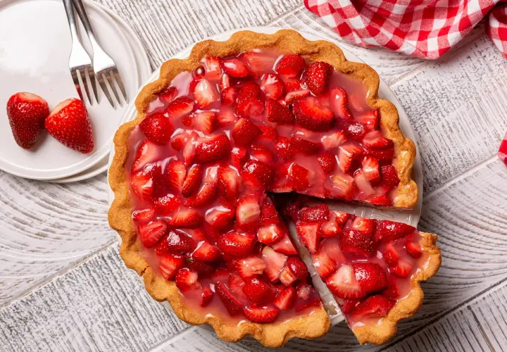 Une part de tarte aux fraises de grand-mère, garnie de fruits frais et de glaçage brillant, prête à être dégustée.