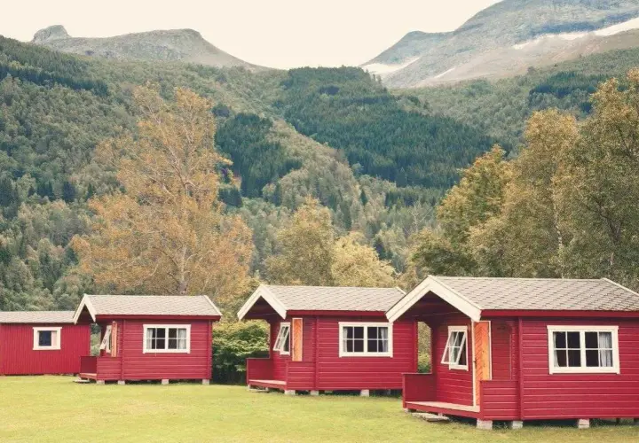 Czerwone domki kempingowe w malowniczej scenerii górskiej, idealne na camping w Norwegii.