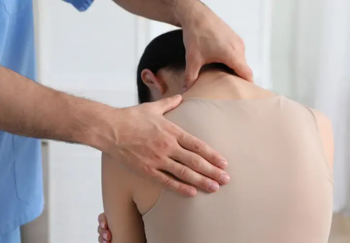 Fizjoterapeuta masuje kark pacjentki, pomagając jej pozbyć się bólu i napięcia, które mogą prowadzić do powstania tzw. wdowi garb.