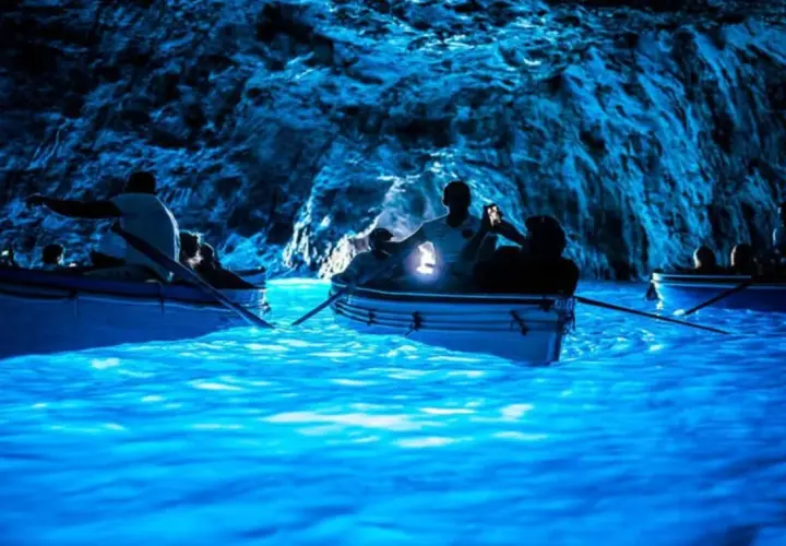 Barche a remi navigano nelle acque luminose della Grotta Azzurra, un luogo magico dove si trova questo spettacolo naturale.