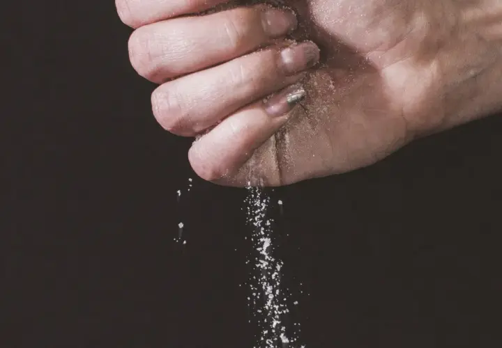 Une main saupoudre du sel, une expression culinaire qui sublime les saveurs.