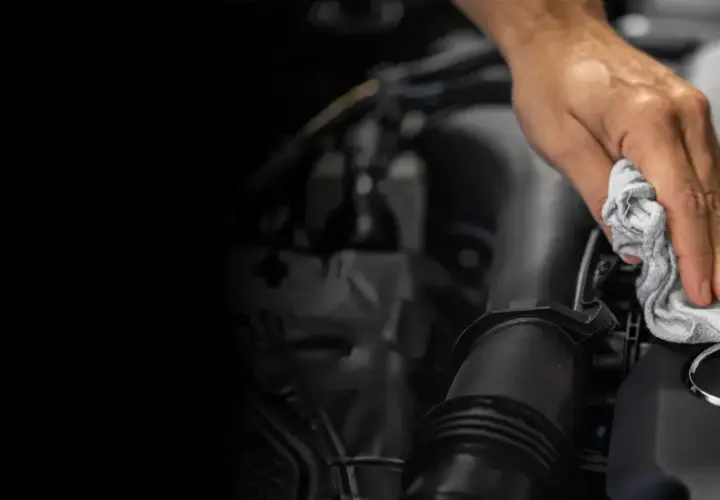 Mano limpiando el logo de Mercedes-Benz. Un detalle para el reset mantenimiento Mercedes.