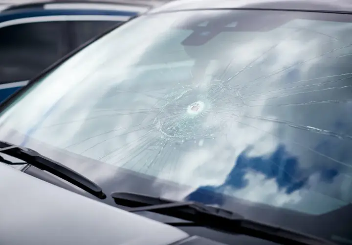 Parabrisas delantero de coche con una gran grieta en forma de telaraña, necesita un cambio.