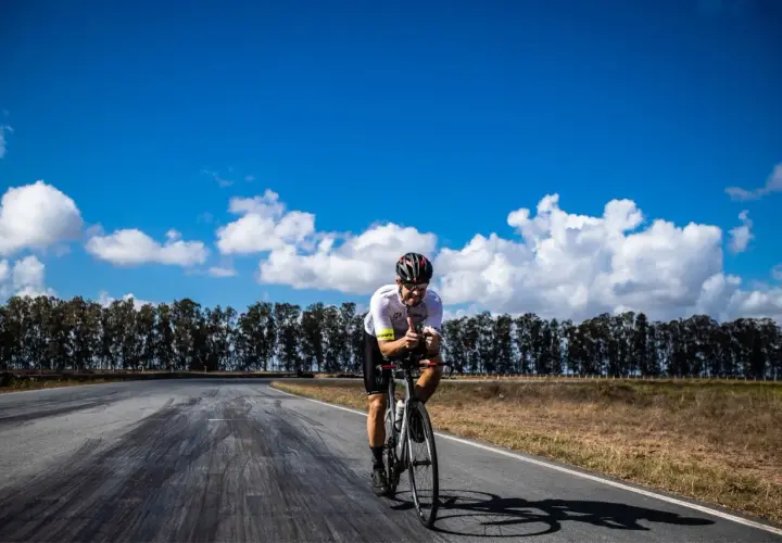 Ciclista pedaleando en la Vía de la Plata en bici, con pulgares arriba bajo un cielo azul y nubes blancas.
