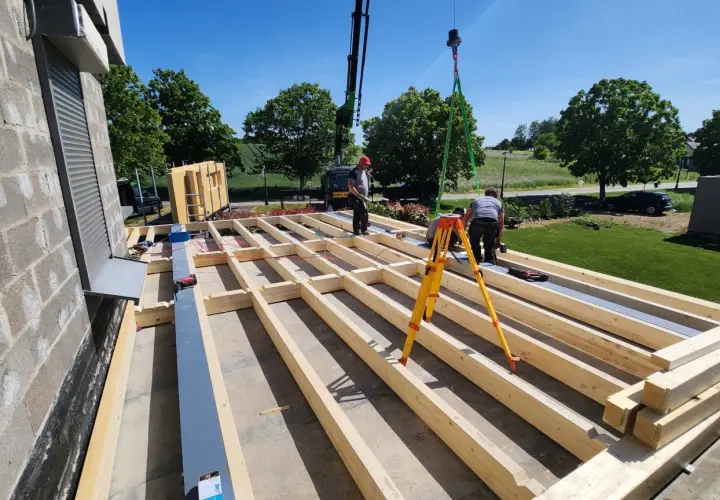 Construction d'une surélévation bois. Des ouvriers installent la structure en bois d'un étage supplémentaire, avec une grue en arrière-plan.