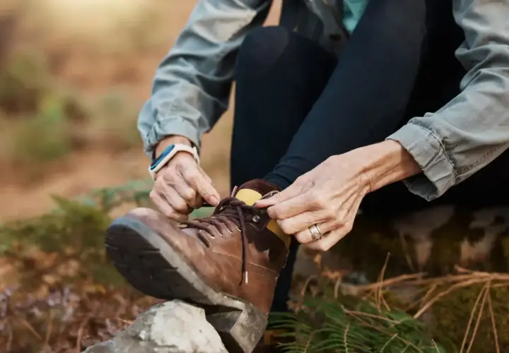 A person demonstrates how to lace boots, preparing for an outdoor adventure.