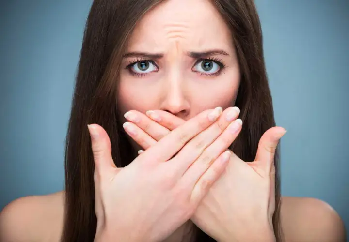 Donna con mani sulla bocca, espressione preoccupata, forse per la salivazione eccessiva.
