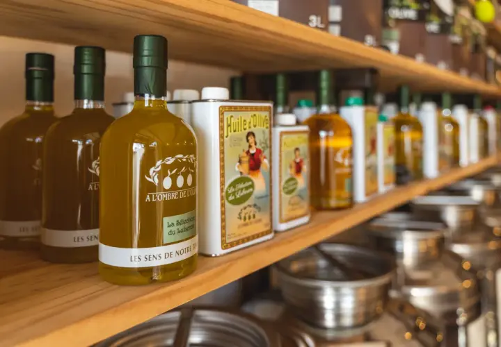 Bouteilles d'huile d'olive "Les Sens de Notre Terre", "A l'ombre de l'Oli" et "La Sélection du Luberon", évoquant les saveurs des terrasses d'Adrien.