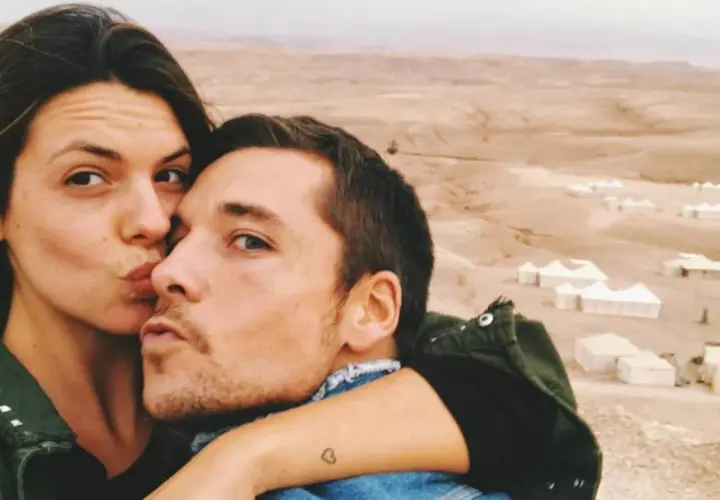 Laura Matamoros y Benji se dan un tierno beso en un paisaje desértico con tiendas de campaña.