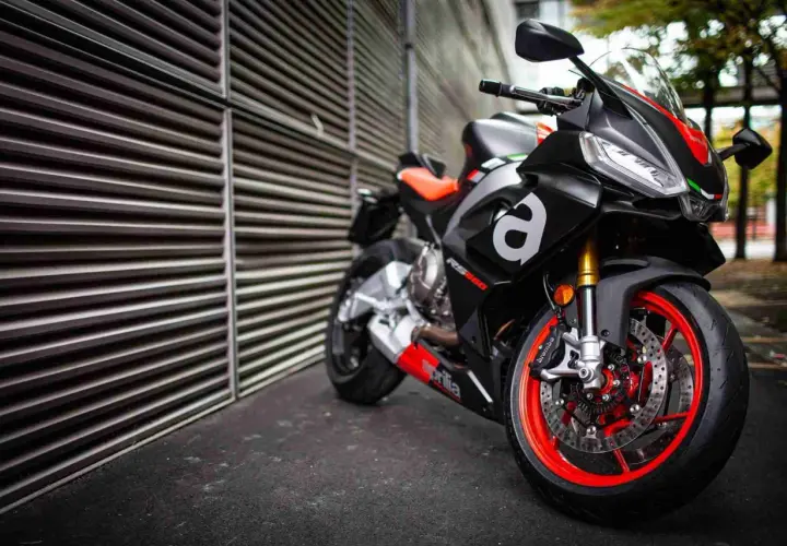 Aprilia RS 660, una moto deportiva negra con detalles rojos y naranjas, lista para la acción.