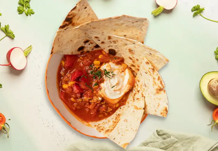 Meksykańska zupa sopa de tortilla z tortillą, śmietaną, kukurydzą i pomidorami.