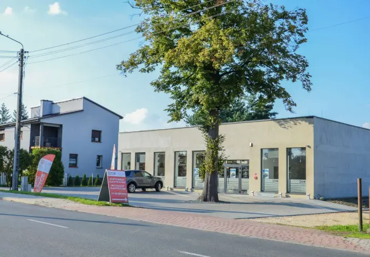 Nowoczesna hurtownia elektryczna w Imielinie. Obok budynku rośnie okazałe drzewo.