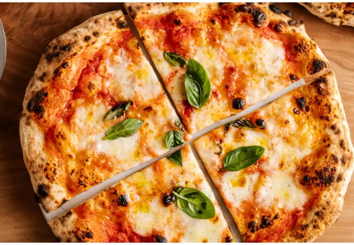 Margherita z puszystym ciastem i prawdziwym sosem do pizzy, ozdobiona świeżą bazylią.