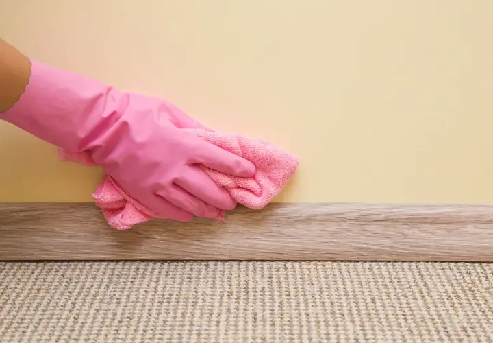 Mano con guanto rosa pulisce la pittura lavabile con un panno rosa.