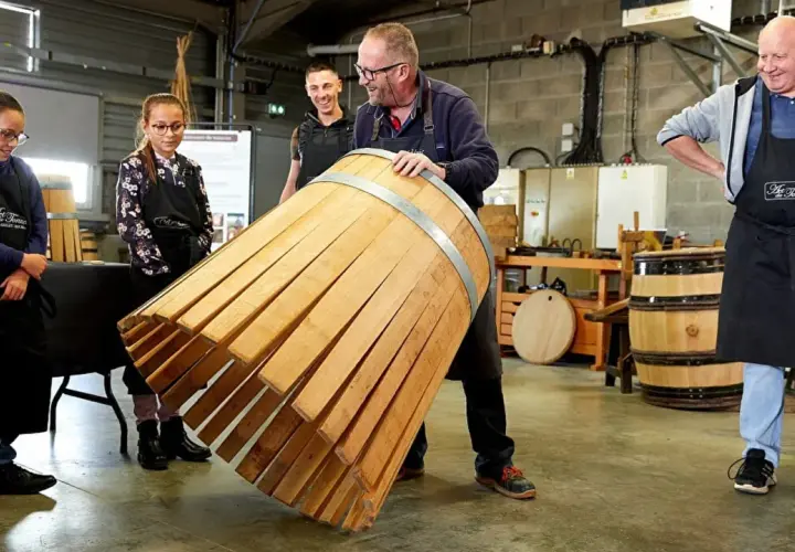 Visite tonnellerie Bourgogne : un maître tonnelier montre un fût en cours de fabrication à des apprentis.