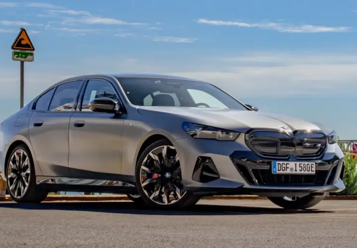 Srebrne BMW 520 z czarnymi akcentami stoi na tle błękitnego nieba i morza.