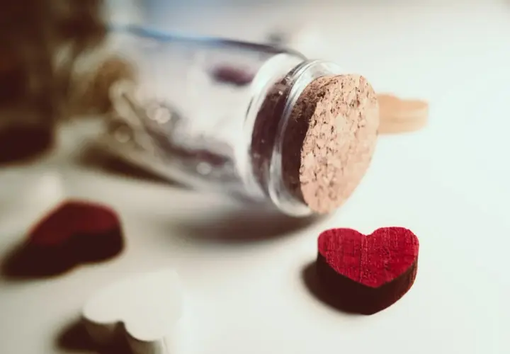 Cuore rosso vicino a una bottiglia tappata, simbolo di innamoramento e amore.