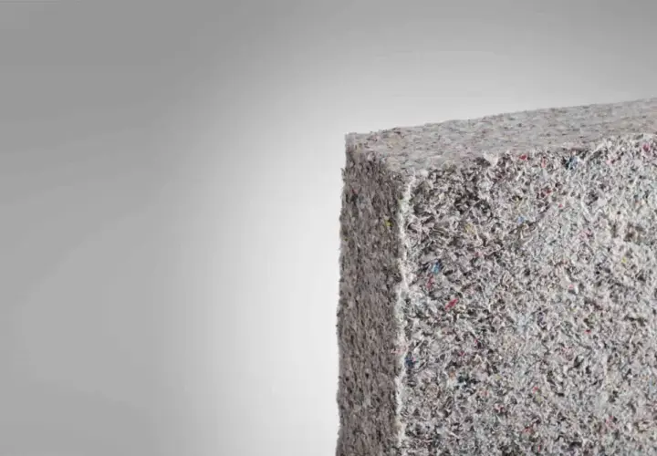 Bloque de material aislante grisáceo, similar a fibra de vidrio triturada. Evitar respirar estas partículas para prevenir consecuencias.