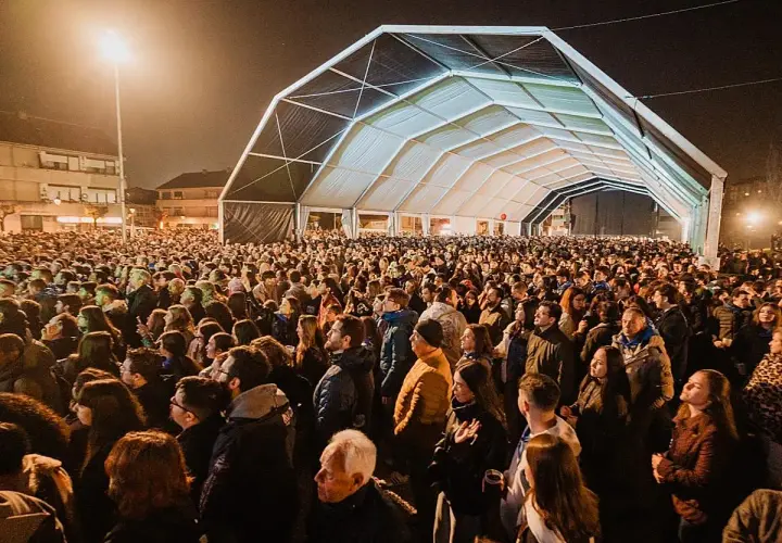 Multitudinaria asistencia al concierto astillero hoy bajo una gran carpa. La gente disfruta de la música y el ambiente nocturno.