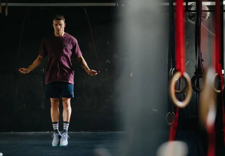 Mężczyzna w sportowym stroju skacze na skakance w siłowni.
