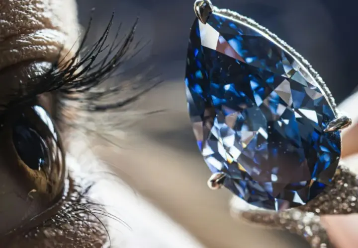 Ein Auge blickt auf einen funkelnden blauen Diamanten, dessen Wert unermesslich ist.