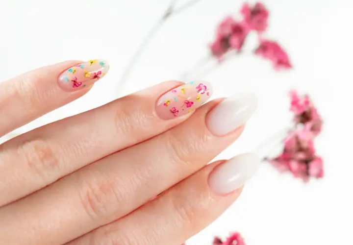 Delikatne, przezroczyste paznokcie z zatopionymi suszonymi kwiatami. Uroczy manicure w wiosennym stylu.