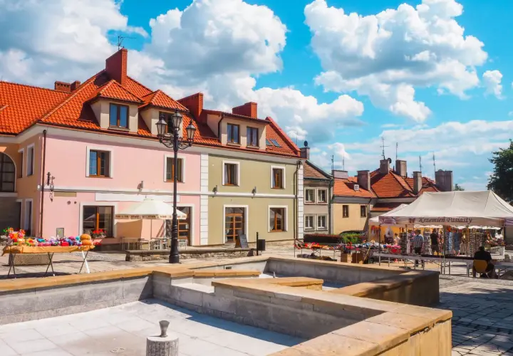 Sandomierz rynek tętni życiem. Kolorowe kamienice, stragany z pamiątkami i błękitne niebo tworzą malowniczy widok.