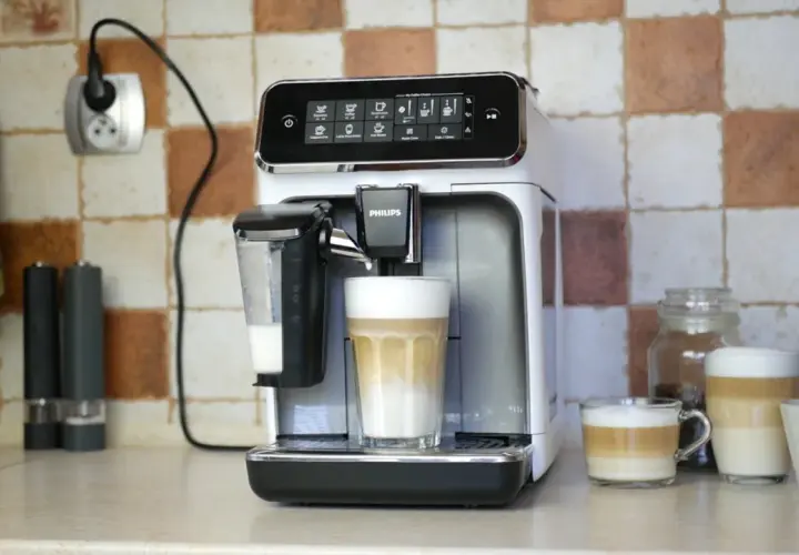 Philips LatteGo 3200 w trakcie czyszczenia obiegu mleka. Na blacie stoi ekspres, obok niego szklanka z kawą latte.